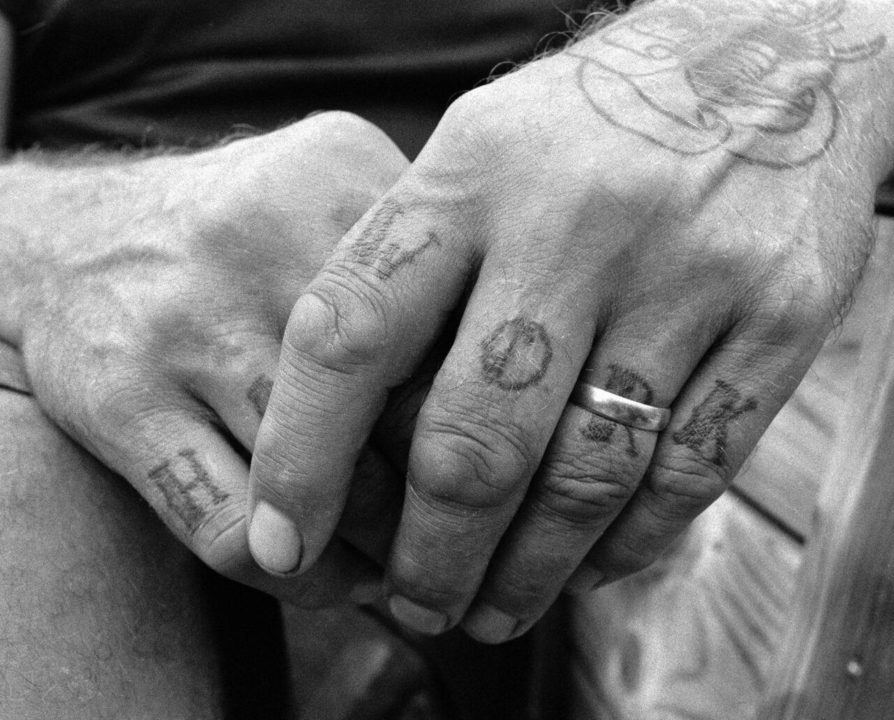 Hand with the text hard work tattooed on the knuckles